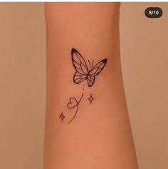 a small butterfly tattoo on the wrist with hearts and stars around it's wings