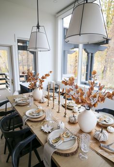 a dining room table with plates and place settings on it, along with vases filled with flowers