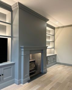 an empty living room with built - in bookcases and fireplace