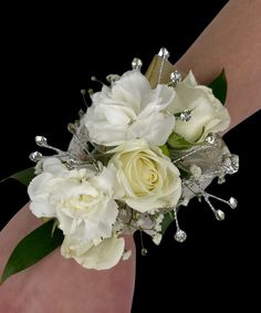 a bridal bouquet with white flowers and crystal beads on the wrist is being held by someone's hand