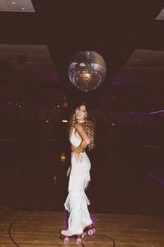 a woman standing on top of a wooden floor next to a disco ball