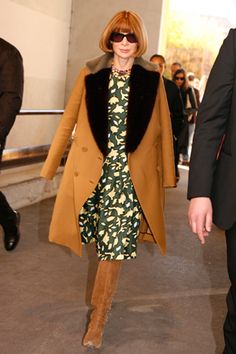 a woman in a dress and coat is walking