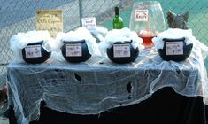 a table topped with lots of bottles of wine next to a chain link fence covered in netting