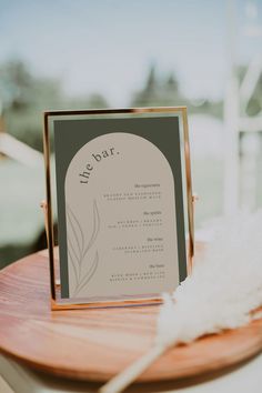 a table with a menu on it and a white feather sitting next to the sign