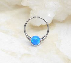 a silver ring with a blue bead around it on top of a white rock