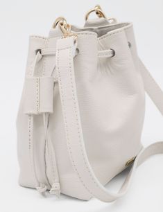 Introducing our elegant small Authenticity purse, crafted from genuine leather that exudes sophistication and timeless style. The detachable and adjustable cross body shoulder strap ensures versatile carrying options for any occasion. This bucket bag, with its two pull double cord drawstrings, is the perfect blend of luxury and practicality. ETHICALLY HANDCRAFTED BY STIVALI MEASUREMENTS: Length: 7" Width: 5" Height: 8" FEATURES/MATERIALS: Smooth leather Detachable & Adjustable cross body shoulde Everyday Luxury Cream Leather Bags, White Bucket Bag With Leather Handles, Classic Beige Bucket Bag With Detachable Strap, Classic Cream Bucket Bag For Everyday Use, Cream Bucket Bag With Detachable Strap For Daily Use, Cream Bucket Bag With Detachable Strap, Classic Cream Bucket Bag For Daily Use, Luxury Everyday Bucket Bag With Leather Handles, Beige Leather Bucket Bag With Adjustable Strap