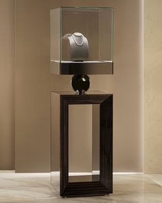 a black vase sitting on top of a wooden table next to a glass display case