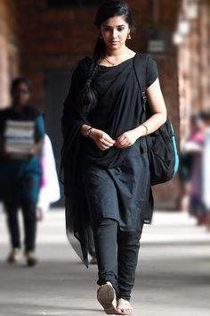 a woman is walking down the street in black