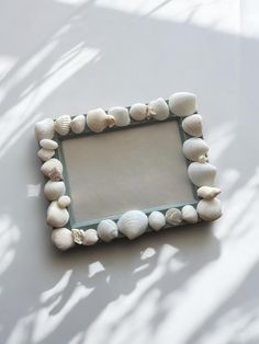 there is a small mirror made out of seashells on the wall with shadow