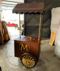 an old fashioned ice cream cart is parked in a garage with the door open and umbrella over it