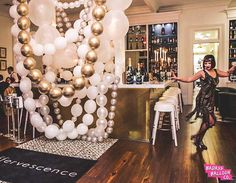 a woman standing in front of a bar filled with balloons