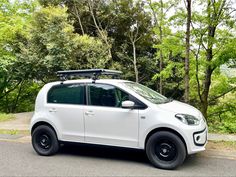 a white car parked on the side of a road with trees in the back ground