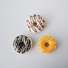 three donuts with chocolate and sprinkles are on a white table top