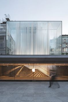 an apple store in the middle of a city with lots of glass walls and stairs