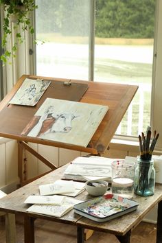 an artist's easel sitting in front of a window filled with art supplies