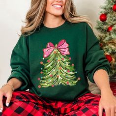 Coquette Pink Bow Christmas Tree Sweatshirt, Stylish Festive Crewneck, Unique Holiday Gift for Best Friend 🕒 PRODUCTION TIME: 1-3 businese days (Usually 2 days) 🚚 SHIPPING TIME: 2-5 businese days (Usually 3 days) 📄 PRODUCT DESCRIPTION: Gildan Short Sleeve Unisex T-shirt Exceptionally cotton with a premium print. 100% cotton (fibre content may vary for different colors) Medium fabric (5.3 oz/yd² or 180 g/m²) Fits true to size Our Unisex Tee is a relaxed fit that feels soft and cozy. Men may fi Green Holiday Sweatshirt For Fall, Green Fall Holiday Sweatshirt, Holiday Green Cotton Sweatshirt, Green Cotton Holiday Sweatshirt, Green Long Sleeve T-shirt For Holiday, Green Christmas Crew Neck Sweatshirt, Green Long Sleeve Tops As Gift, Bow Christmas Tree, Bow Christmas