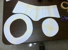 paper cut out to look like an eye with scissors and tape on the table next to it