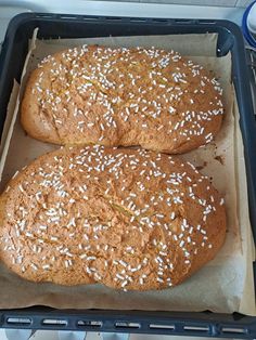 two loaves of bread sitting on top of a baking pan covered in white sprinkles