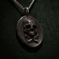 This delicate Skull&Crossbones pendant is a very subtle yet very detailed piece, perfect to complete any wardrobe. The oval shape features a skull and crossbones design in the front, and has the Book of Alchemy logo engraved in the back. This Sterling Silver piece measures 19mm from top to bottom, or 23mm with the eye included. Both 42cm and 70cm chains are available to make sure the necklace compliments the look you're going for. The Skull&Crossbones pendant is perfect to combine with t Alchemy Logo, Skull Crossbones, Biker Rings, A Skull, The Skull, Skull And Crossbones, Wooden Case, Silver Pieces, Jewelry Lover