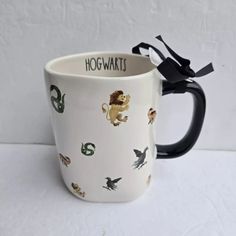 a harry potter coffee mug with hogwarts on the front and black handles, sitting on a white surface