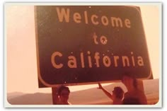 three people holding up a welcome to california sign