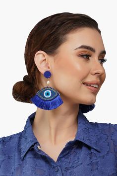 a woman wearing large blue earrings with an evil eye on the front and back of her ear