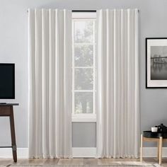 a living room with white curtains and a tv