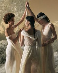 three women in white dresses holding hands together