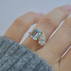 a woman's hand wearing a ring with an aqua blue and white topaz