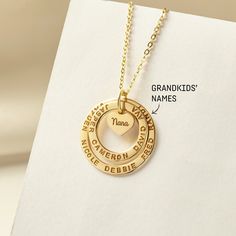 "These two rings are stamped with her loved one and a small heart charm at the center to share their love with family members. The heart charm can be engraved with however you call your grandma: nana, mimi, abuela, omi, gigi - just whichever dear to you! A perfect gift for Grandma on any occasion. ► GRANDMA NECKLACE WITH KIDS NAMES * WORD LIMIT: Small ring: 4-5 words / Big ring: 6 words. Date is counted as 2 words. *  Small ring measures approx. 3/4\" (20mm). Big ring measures approx. 1\" (26mm) Name Necklace For Anniversary Gift, Heart-shaped Name Jewelry For Anniversary, Personalized Name Charm Necklaces, Heart Shaped Jewelry With Names For Anniversary, Personalized Open Heart Charm Necklace For Anniversary, Hand Stamped Double Heart Jewelry For Anniversary, Engraved Necklace For Valentine's Day, Anniversary Hand Stamped Double Heart Necklace, Hand Stamped Yellow Gold Charm Necklace For Anniversary