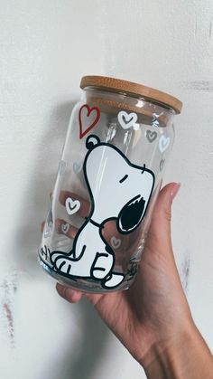 a hand holding a glass with a cartoon dog painted on the side and hearts around it