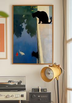 an old record player sitting on top of a table next to a painting and lamp