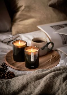 two candles are sitting on a wooden tray