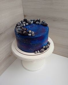 there is a blue cake with berries on it