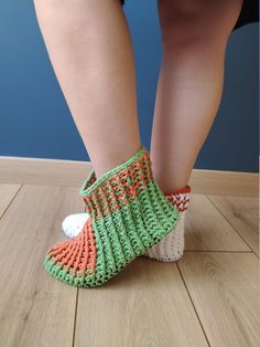 a woman's legs with crocheted socks and slippers on the floor