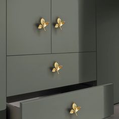 two drawers with gold butterflies on them in front of a gray wall and carpeted floor