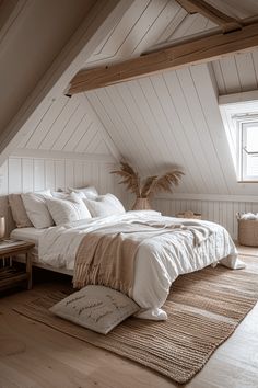 a large bed sitting in the middle of a bedroom under a slanted ceiling next to a window