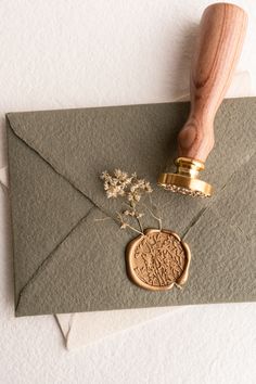 a wax stamp on top of an envelope with flowers and a rubber stamper next to it