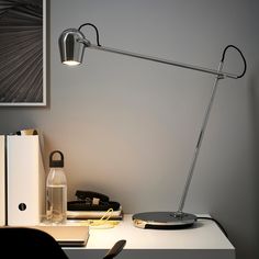 a desk lamp sitting on top of a white table next to a book and other items