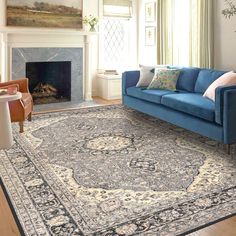 a blue couch sitting in front of a fireplace next to a rug on top of a hard wood floor