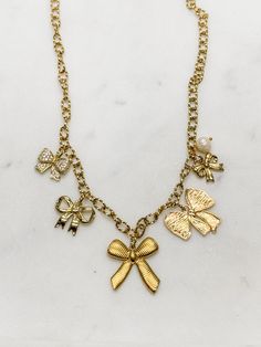 If you love a classic bow, this fun charm necklace is your vibe! Handcrafted in our studio from 18k gold-plated steel elements. --18" in length and will clasp shorter as desired --Hypoallergenic --Tarnish resistant --Plated in genuine 18k gold --Trendy design, but with the timeless appeal of bow ribbons These will be limited, so get yours while it's available! Chic Charms Jewelry As A Gift, Chic Charms Jewelry For Gifts, Chic Charms Jewelry As Gift, Chic Jewelry Charms For Gifts, Chic Charm Jewelry For Gifts, Elegant Gold-tone Necklaces With Dangling Charms, Elegant Gift Charms With Adjustable Chain, Chic Gold Necklaces With Charms, Elegant Gold-tone Charm Necklace With Vintage Charm