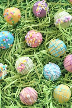 there are many different colored chocolate eggs in the grass with sprinkles on them