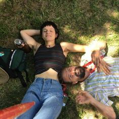 two people laying on the ground with their arms around each other and one person holding an object