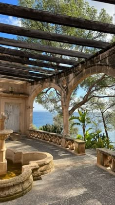 an outdoor area with water fountain and wooden pergolan roof over looking the ocean