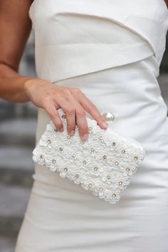 Fiorella Minaudiere Elevate your style with the Fiorella Minaudiere. This luxurious clutch is adorned with delicate flowers, sparkling rhinestones, and a classic faux pearl clasp. Its versatile design allows you to carry it as a clutch or use the detachable chain for a more effortless look. Perfect for any occasion, this elegant purse will be your go-to accessory. Elegant White Evening Bag, Elegant Pearl White Clutch For Events, Elegant White Evening Bag With Pearl Handle, Elegant White Clutch For Events, Elegant White Clutch For Formal Occasions, Elegant White Formal Clutch, Elegant Pearl-embellished Evening Bag For Formal Occasions, Elegant Pearl White Clutch Evening Bag, Chic Pearl White Clutch For Events