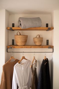 two wooden shelves with baskets and clothes hanging on them