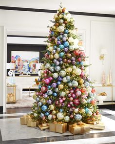 a brightly colored christmas tree with presents on the bottom and gold boxes underneath it, in a living room