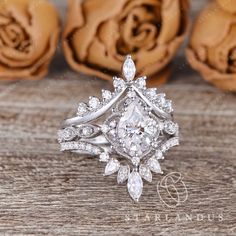 a diamond ring sitting on top of a wooden table with roses in the back ground