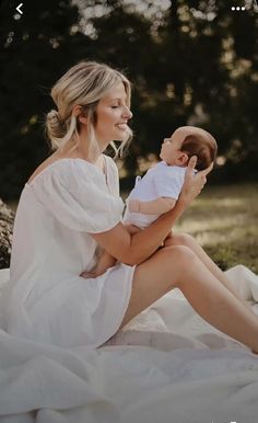 a woman sitting on the ground holding a baby