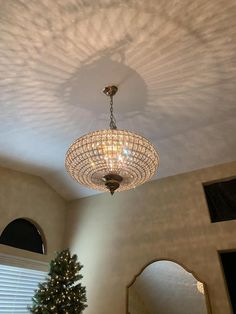 a chandelier hanging from the ceiling in a living room next to a christmas tree